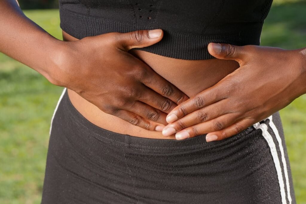 Mulher com as mãos na barriga preoculpada com sua saúde digestiva.